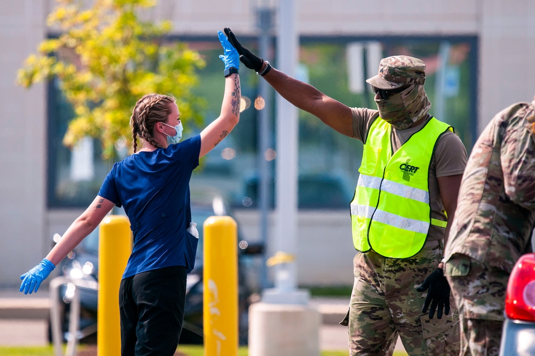 Guardsmen wearing protective gear high-five.