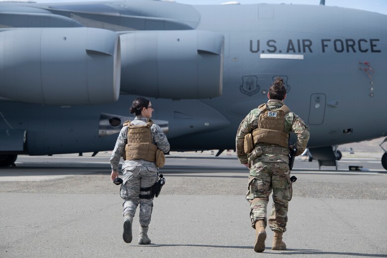 U.S. Air Force Airman 1st Class Stephanie DaSilva, left, 60th Security Forces Squadron installation entry controller, and Staff Sgt. Brenden Rinehart, 60th SFS patrolman, walk toward a C-17 Globemaster III May 16, 2020, during security check on the flight line at Travis Air Force Base, California. The C-17 is one of three aircraft assigned to Travis AFB and is often called upon to support mobility missions. (U.S. Air Force photo by Tech. Sgt. James Hodgman)