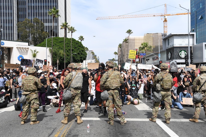 Service members stand in front of protesters.