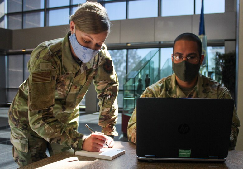 Second Lt. Laura Pulliam, 50th Comptroller financial operations commander, left, jots down notes as Tech. Sgt. Jon Carlos Candelario, 50th CPTS flight financial operations chief, views the new Comptroller Services Portal July 1, 2020, at Schriever Air Force Base, Colorado. The CSP will allow Airmen to submit requests such as military, civilian and travel pay through an online process. (U.S. Air Force photo by Marcus Hill)
