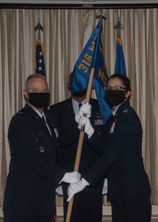 Col. Tyler Schaff, 316th Wing and Joint Base Andrews commander, passes the 316th Mission Support Group guidon to Col. Nichole Scott, 316th MSG commander, during an assumption of command ceremony at JBA, Md., July 2, 2020.