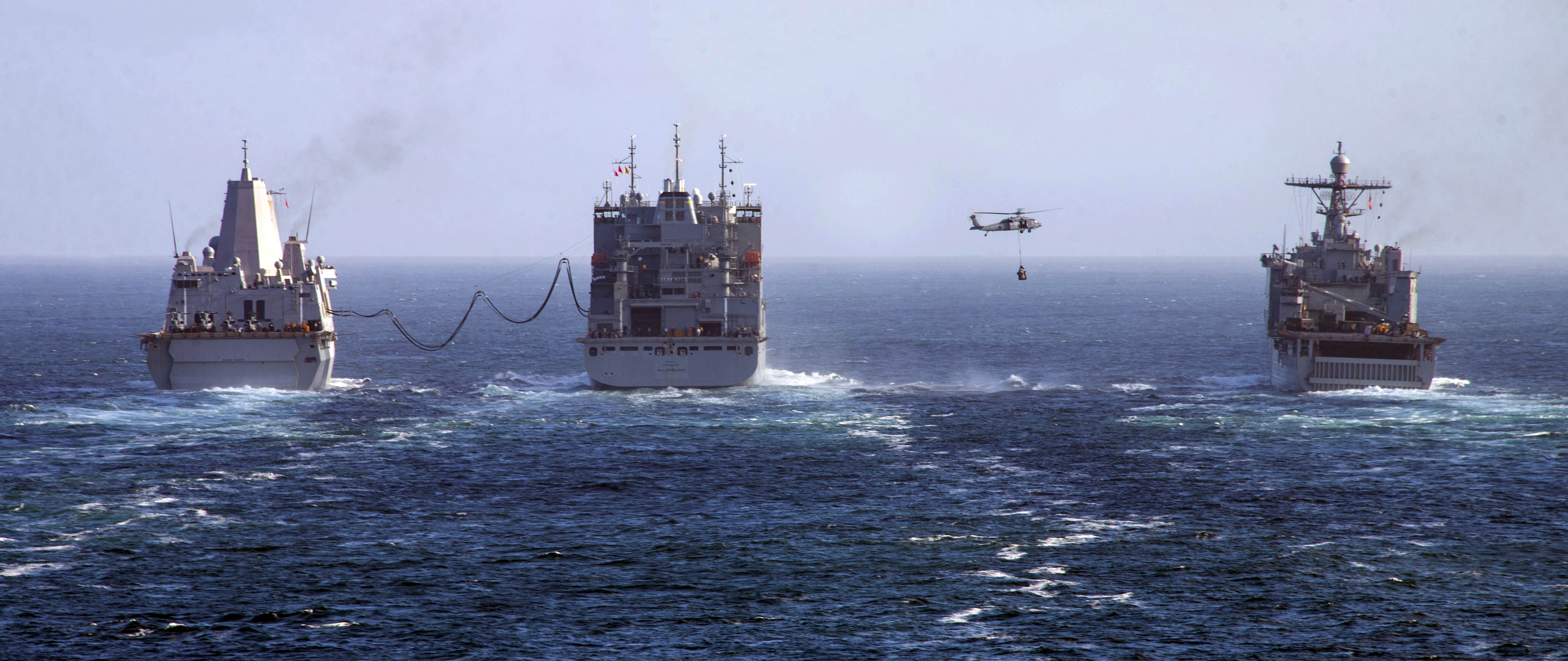 USS New York (LPD 21), left, and the Harpers Ferry-class dock landing ship USS Oak Hill (LSD 51), right, conduct a replenishment-at-sea with the Lewis and Clark-class dry cargo and ammunition ship USNS William McLean (T-AKE 12).