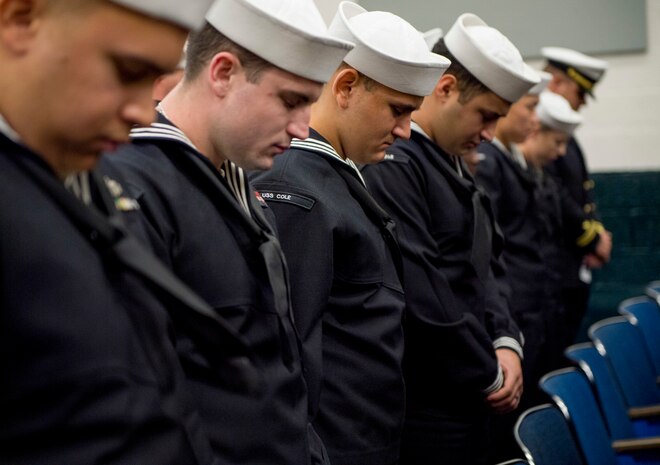 Sailors assigned to the guided-missile destroyer USS Cole (DDG 67) bow their heads in prayer during a remembrance ceremony.