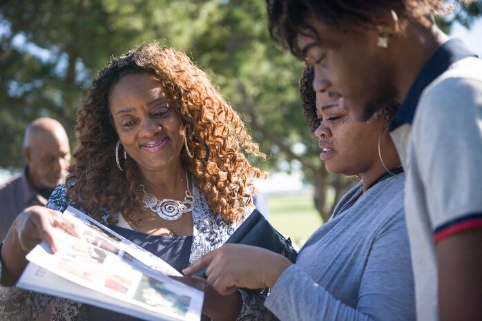 Dianne McDaniels, left, mother of the late Information Systems Technician Seaman James Rodrick McDaniels, who was killed in the USS Cole bombing, shows her grandson, DaiSaan, right, photos of his father from a Cole cruise book at the USS Cole memorial.