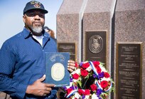 Retired Lt. Elroy Newton poses with his cruise book from the guided-missile destroyer USS Cole (DDG 67).