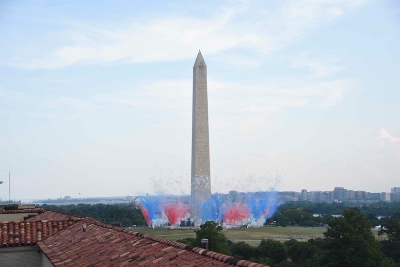 Blue and red smoke plumes erupt around the Washington Monument.