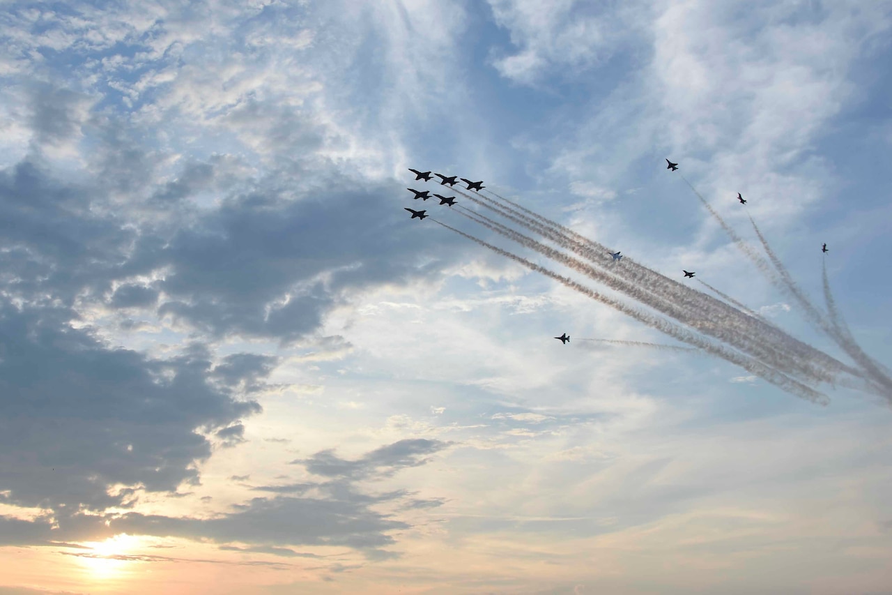 Military aircraft fly through a cloudy sky at dusk.