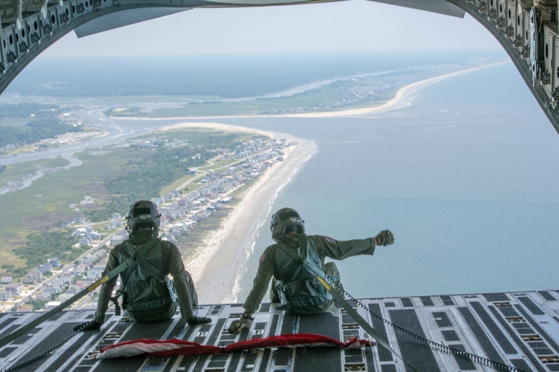Senior Airman Gage Stevens (Left) and Master Sgt. Jim Ebert (Right), both loadmasters, Team Charleston, Joint Base Charleston, S.C. wave to beachgoers down the coast of South Carolina July 4, 2020 from inside a C-17 Globemaster III. The flight was in part to Salute from the Shore.