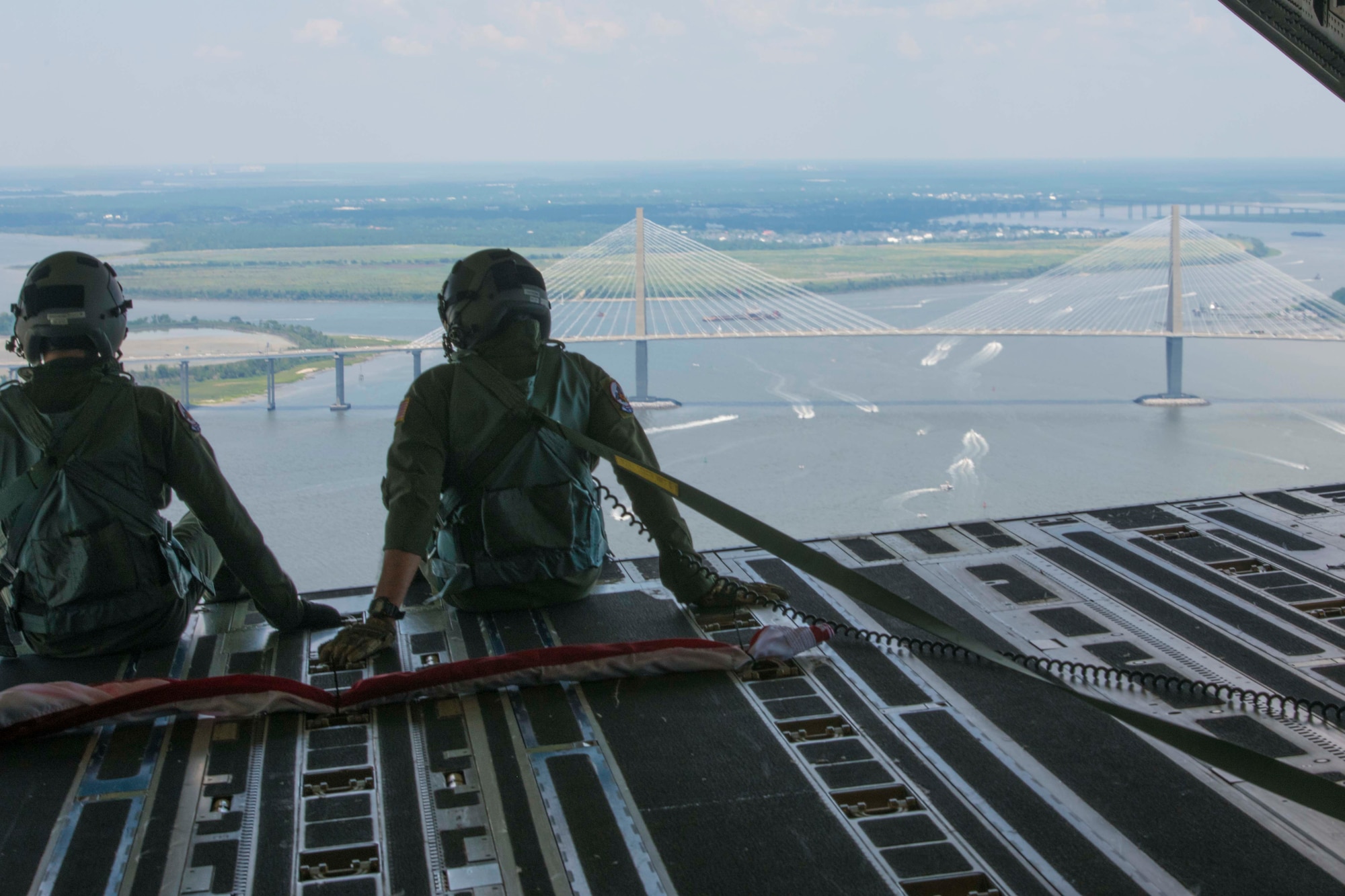 Senior Airman Gage Stevens (Left) and Master Sgt. Jim Ebert (Right), both loadmasters, Team Charleston, Joint Base Charleston, S.C. look out upon the Charleston harbor  July 4, 2020 from inside a C-17 Globemaster III. The flight was in part to Salute from the Shore.