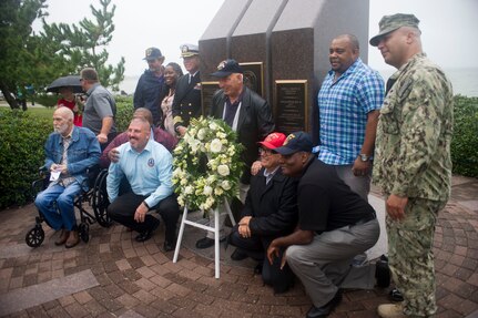 A group of USS Cole (DDG 67) family and friends pose at the USS Cole Memorial to take a commemorative photograph.