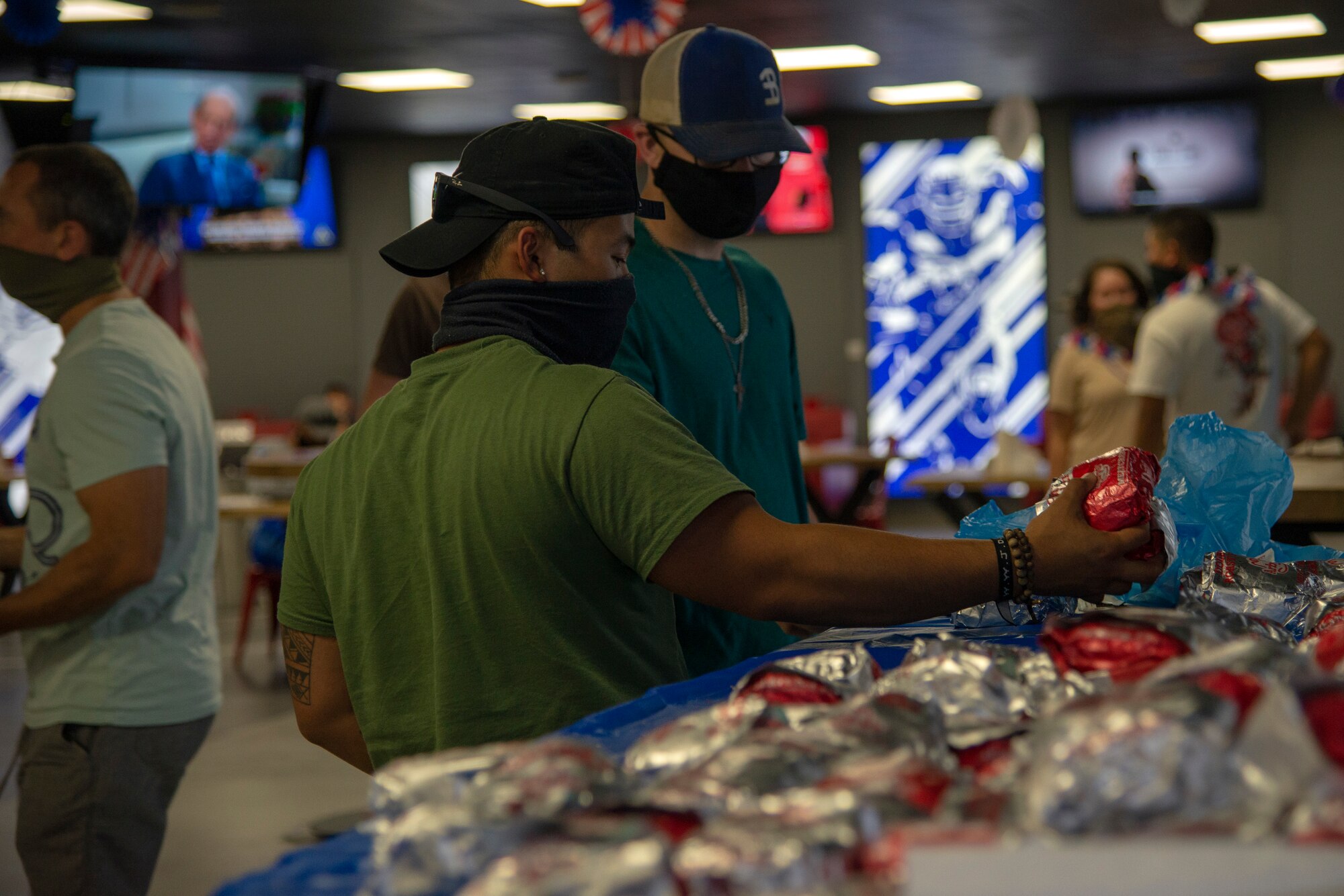 Two service members grab free food at the Fox Sports Bar during an Independence Day celebration, July 4, 2020, Al Udeid Air Base, Qatar. Food was provided free of charge to event attendees to celebrate America’s independence.