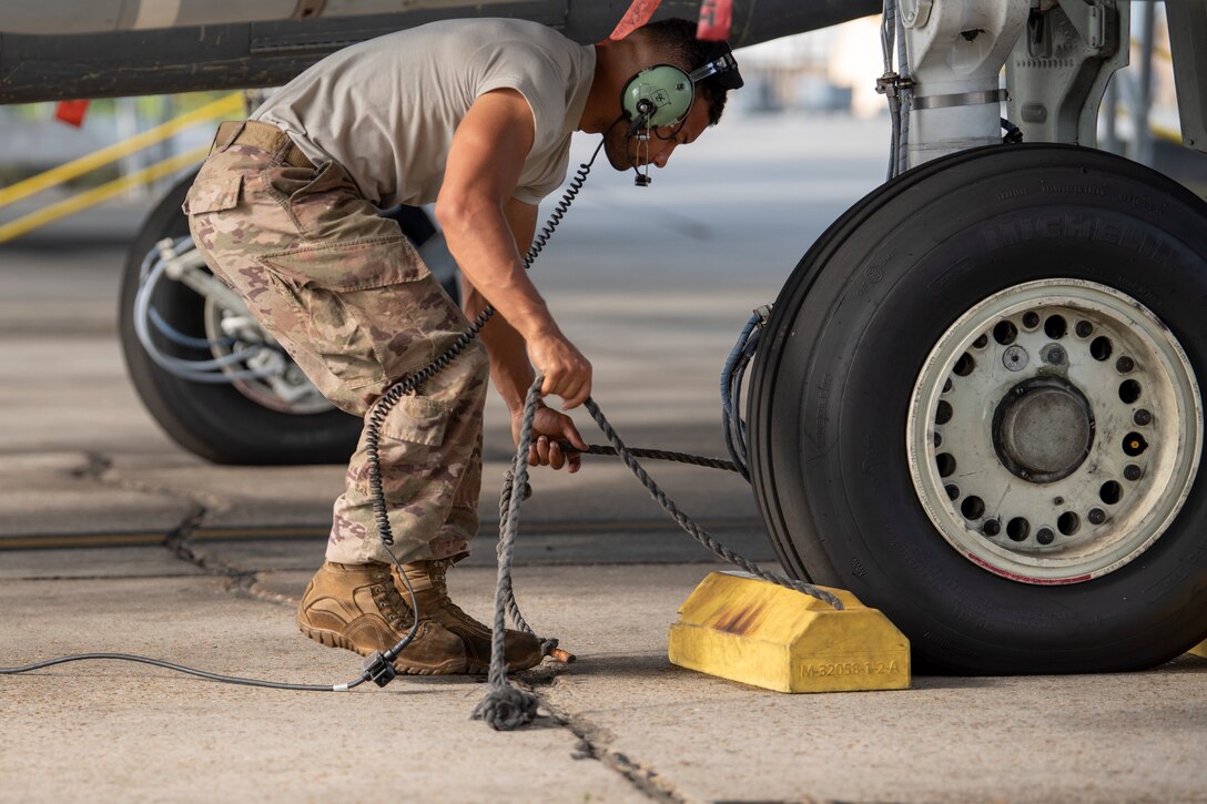 a photo of an airman pulling chalks from under an aircraft