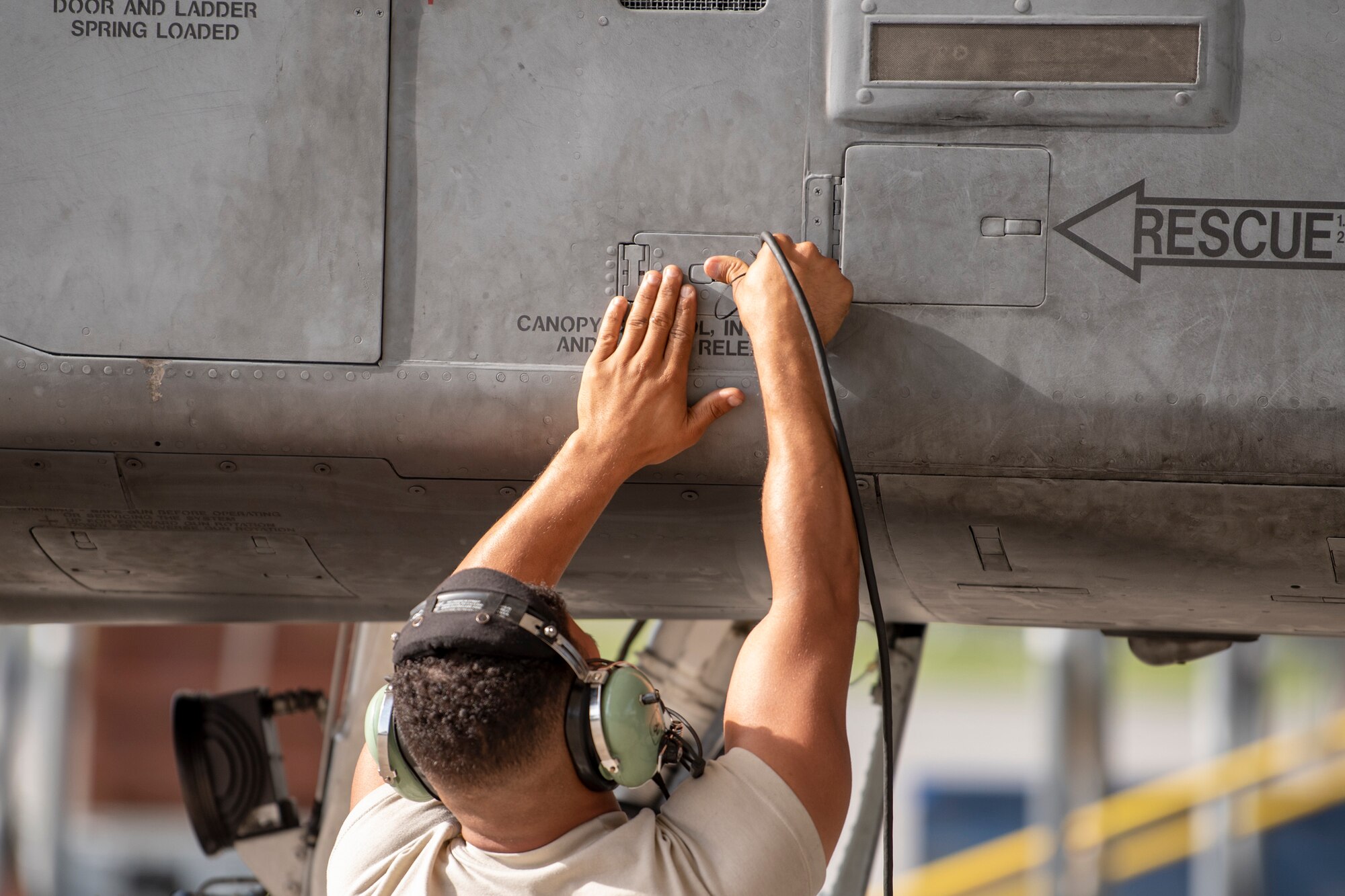 A photo of an Airman closing an aircraft panel