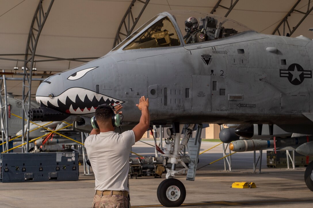 A photo of a crew chief marshaling an aircraft