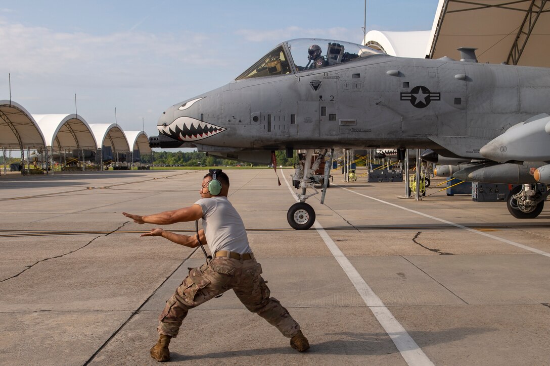 A photo of a crew chief marshaling an aircraft