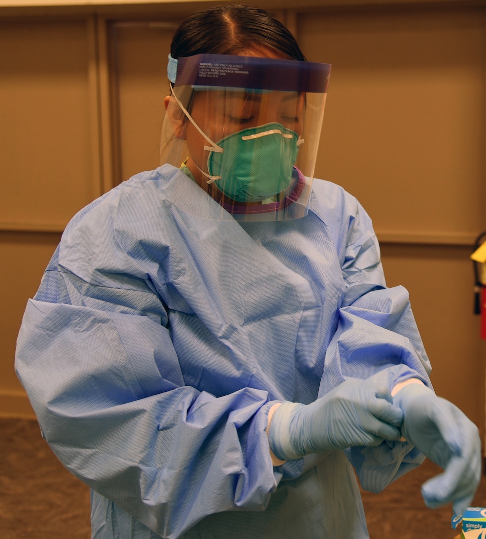 Spc. Paige Curtiss, 253rd Engineer Battalion, food service specialist, puts on personal protection equipment