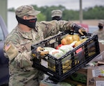 North Carolina Army National Guardsmen Spc. Isai Arroyo, assigned to the 883rd Engineer Company, carries produce to a vehicle