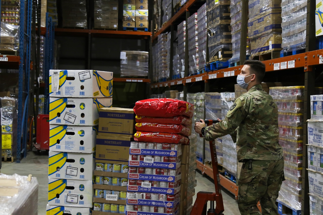 A soldier moves pallets of food at a food bank.