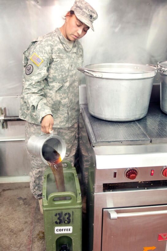 A soldier pours coffee into a large container.