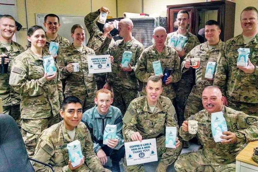 Smiling soldiers hold donated bags of coffee.