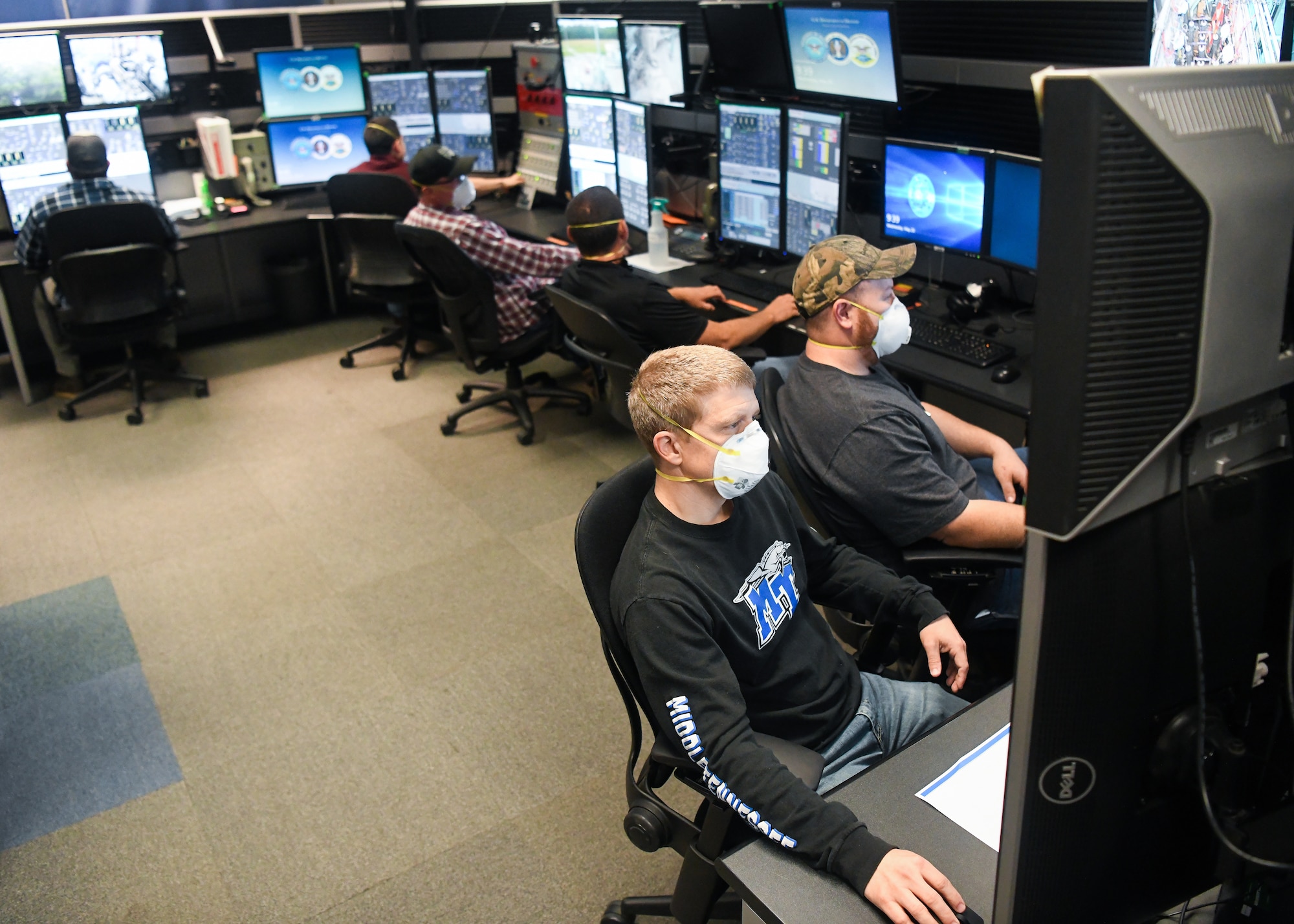 Adam Webb, bottom left, an electrical engineer, Justin Floyd, an outside machinist, and other Team AEDC personnel work in the control room of the Arnold Engineering Development Complex Aerodynamic and Propulsion Test Unit (APTU) May 20 while wearing masks to help mitigate risk associated with the coronavirus pandemic. The APTU team has performed their tasks, providing hypersonic testing capabilities, without interruption during the pandemic. Hypersonics is considered a critical field for national defense. (U.S. Air Force photo by Jill Pickett)