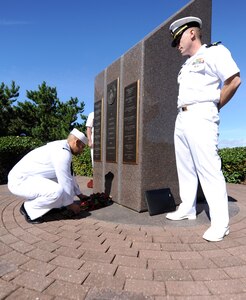 Petty Officer 1st Class Miguel Rodriguez, left, places a bouquet of roses as part of the Roll Call of Heroes during a remembrance ceremony at the Cole Memorial on board Naval Station Norfolk.