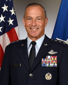 Lt. Gen. Pleus in uniform standing in front of the U.S flag and Airforce flag.