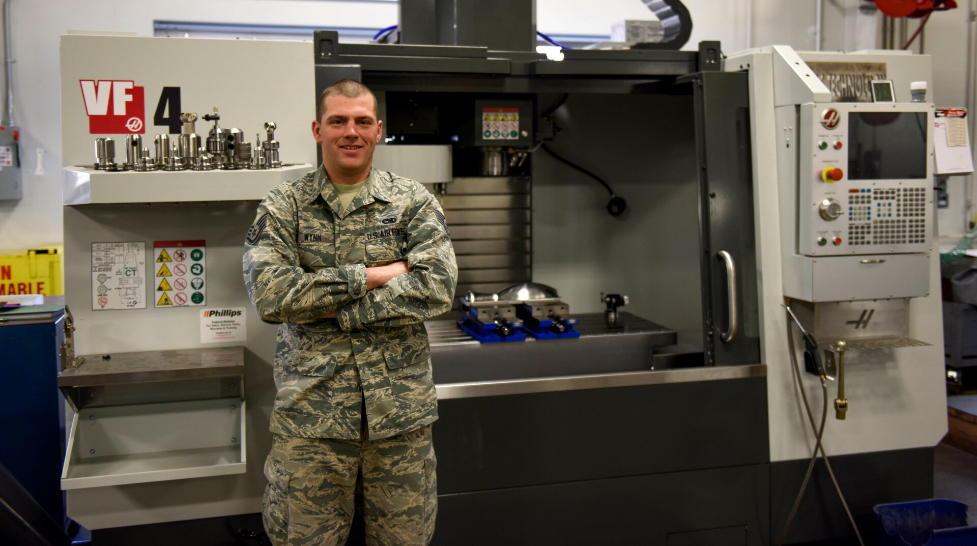 U.S. Air Force Staff Sgt. Alex Wynn, a machinist assigned to the Ohio National Guard’s 180th Fighter Wing, poses in front of a Computer Numerical Control machine at the 180FW in Swanton, Ohio, March 8, 2020. Wynn used a similar machine and knowledge he learned at the 180FW to create a replacement gear for the Wood County Courthouse clock.