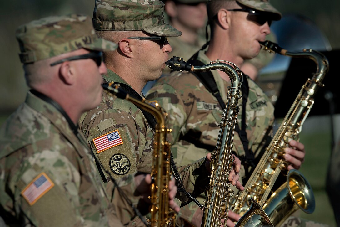 Three guardsmen play the saxophone next to one another.