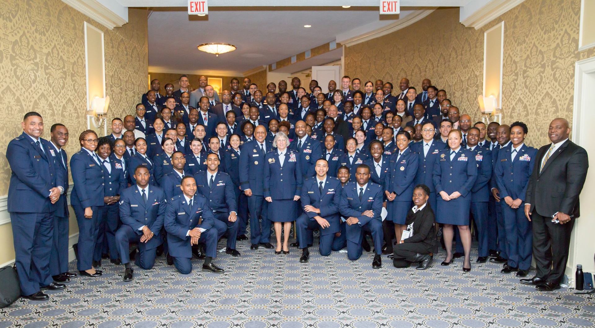 A group of Air Force service members and civil service employees pose for a group photo during a conference.