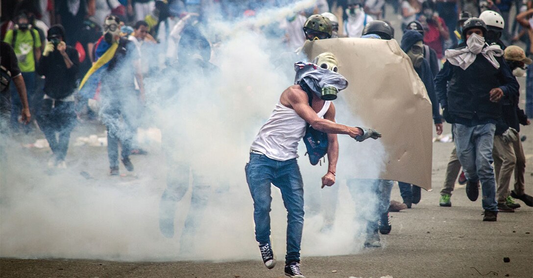 Protester launches tear gas fired by national guard during demonstration against government of Nicolás Maduro, Caracas, Venezuela, April 26, 2017