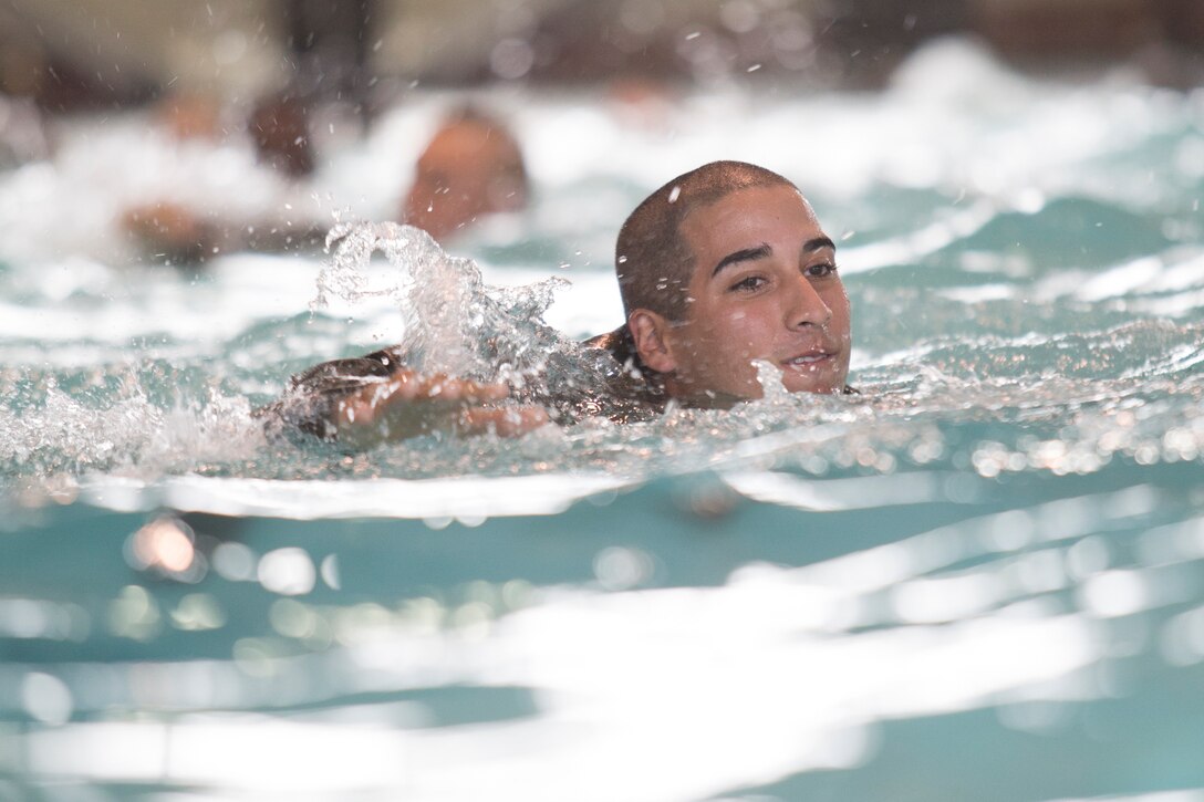 A Marine swims in a pool.