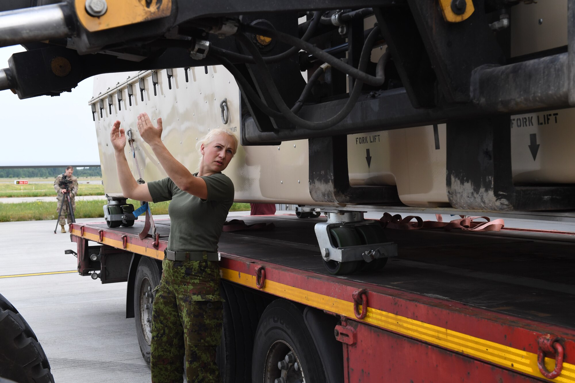 A member of the Estonian air force directs a forklift at Amari Air Base, Estonia, June 29, 2020. For the first time, MQ-9 Reapers from Detachment 2 at Miroslawiec Air Base in Poland deployed to Amari Air Base. (U.S. Air Force photo by Airman 1st Class Alison Stewart)