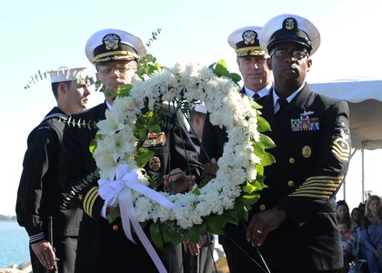 Rear Adm. Christopher W. Grady, Cmdr. James Quaresimo and Command Master Chief Michael Fisher carry a wreath at the USS Cole Memorial during a ceremony at Naval Station Norfolk.