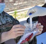 Nevada National Guard Tech. Sgt. Jerzy Horst holds a biohazard bag open for a Soldier who collected a nasal swab sample from a resident during COVID-19 testing in the Shoshone Health District July 1, 2020, in Duckwater, Nevada.