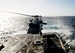 An SH-60B Sea Hawk Helicopter takes off from the flight deck of the guided missile frigate USS Preble (DDG 88). A carriage and tracks for the ship's recovery assistance, securing and traversing (RAST) system are on the deck below the helicopter.