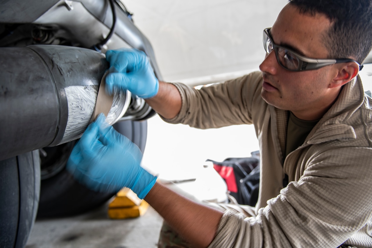 A man wearing protective goggles works on an aircraft.