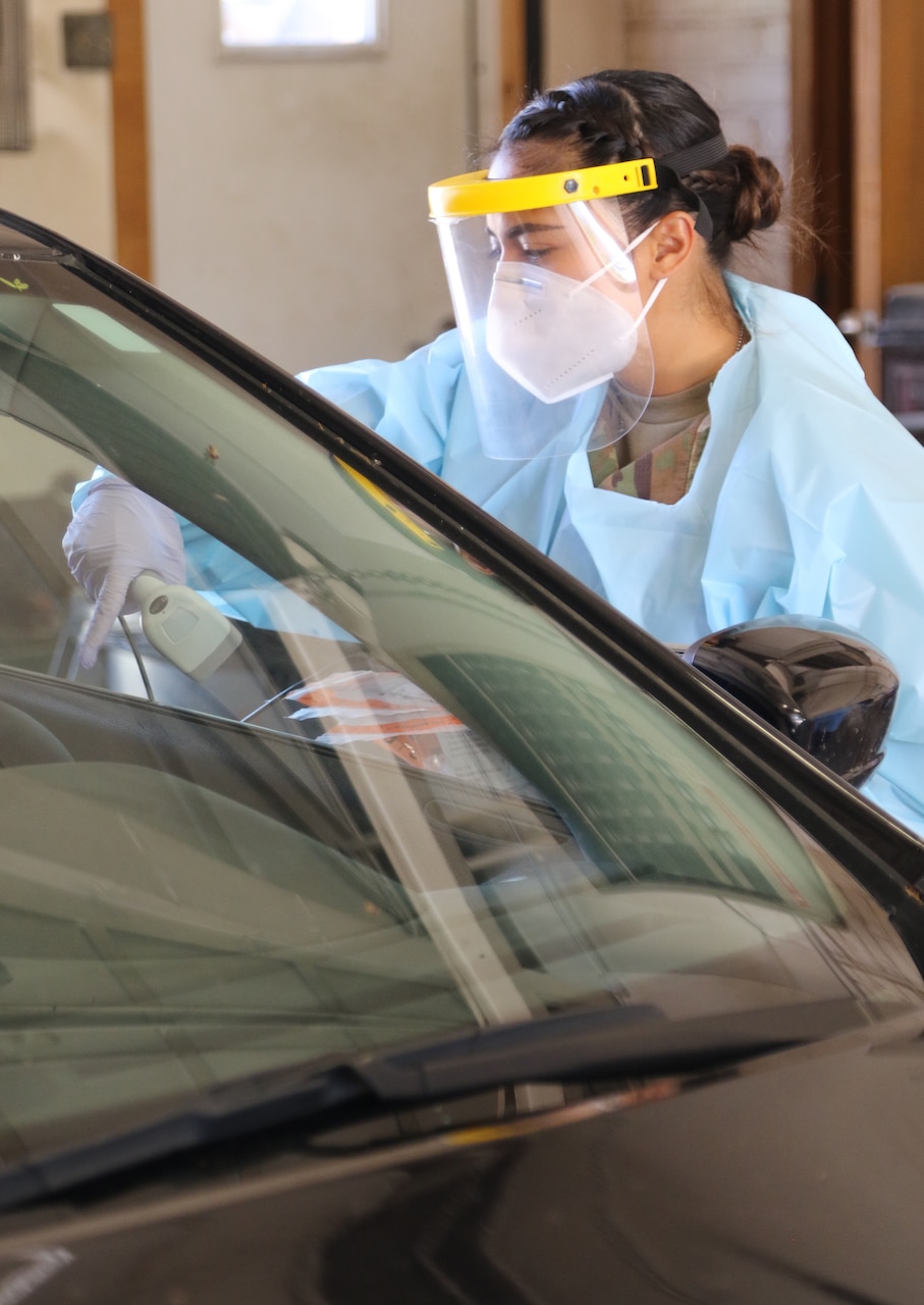 A woman in protective gear stands next to a car.