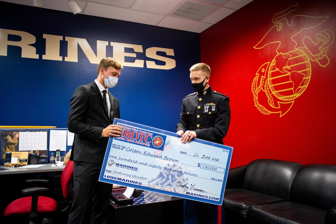 Capt. Michael McDonald, right, the executive officer of Recruiting Station Richmond, presents Colton Brown, left, a senior at Lakeland High School, a Naval Reserve Officers Training Corps Scholarship check at Recruiting Sub-Station Suffolk in Suffolk, Virginia, June 16, 2020. The NROTC scholarship, valued at up to $180,000, will pay for the cost of full tuition, books and other educational fees at many of the country’s leading colleges and universities. (U.S. Marine Corps Photo by Cpl. Niles Lee)