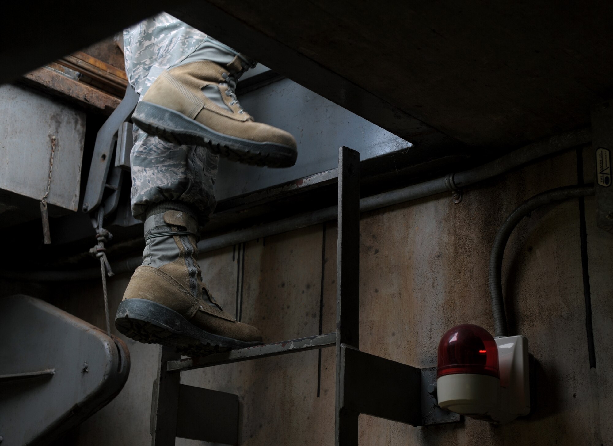 Airmen climbs ladder to exit underground bunker.