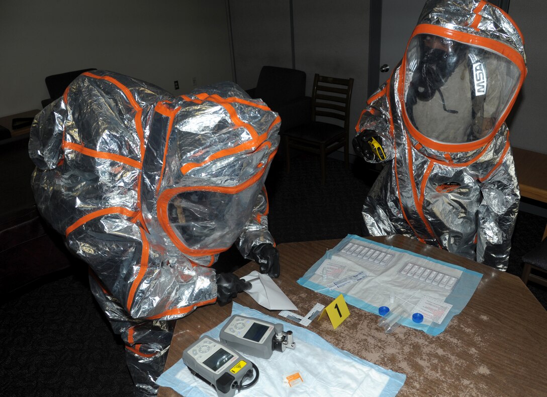 Biochemical engineers in hazmat suits test samples.