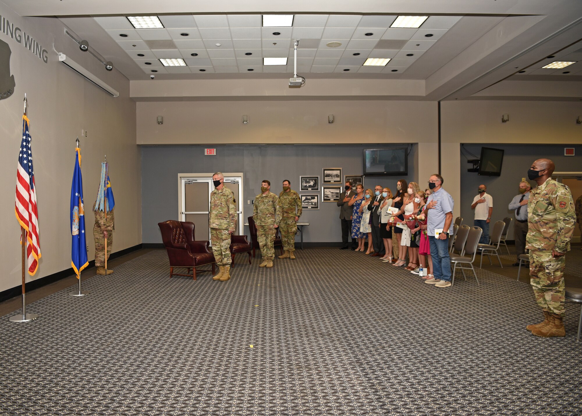 Members and associates of the base, wear masks and social distance when showing respect to the American flag while the national anthem plays at the start of the 17th Logistics Readiness Squadron Change of Command Ceremony at the event center on Goodfellow Air Force Base, Texas, July 8, 2020. With COVID-19 precautions in place, the 17th LRS welcomed their incoming commander, Maj. Joseph Newman, and thanked 17th LRS outgoing commander, Maj. Robbie Walsh, for his hard work and dedication. (U.S. Air Force photo by Airman 1st Class Abbey Rieves)