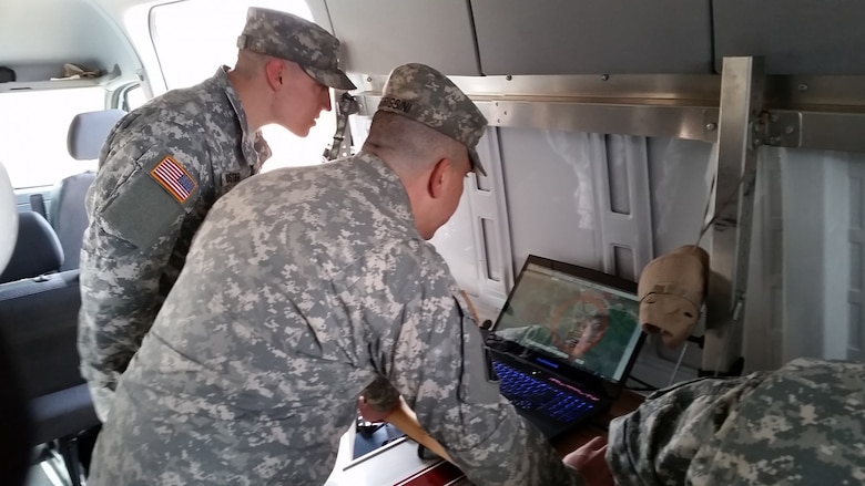 Two soldiers look over a model on a laptop.