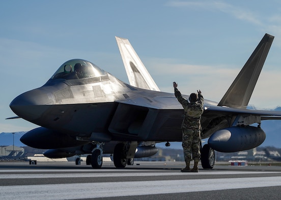 U.S. Air Force Staff Sgt. Christopher Graham, 3rd Wing crew chief, marshalls an F-22 Raptor on the flight line at Joint Base Elmendorf-Richardson, Alaska May 5, 2020. The 90th Fighter Squadron and 90th Aircraft Maintenance Unit recently launched 168 sorties in four days, highlighting their rapid mobility capabilities and response readiness during COVID-19 and the ability to generate combat airpower at a moment’s notice to ensure regional stability throughout the North American Aerospace Defense Command Region and Indo-Pacific. (U.S. Air Force photo by Tech. Sgt. Westin Warburton)