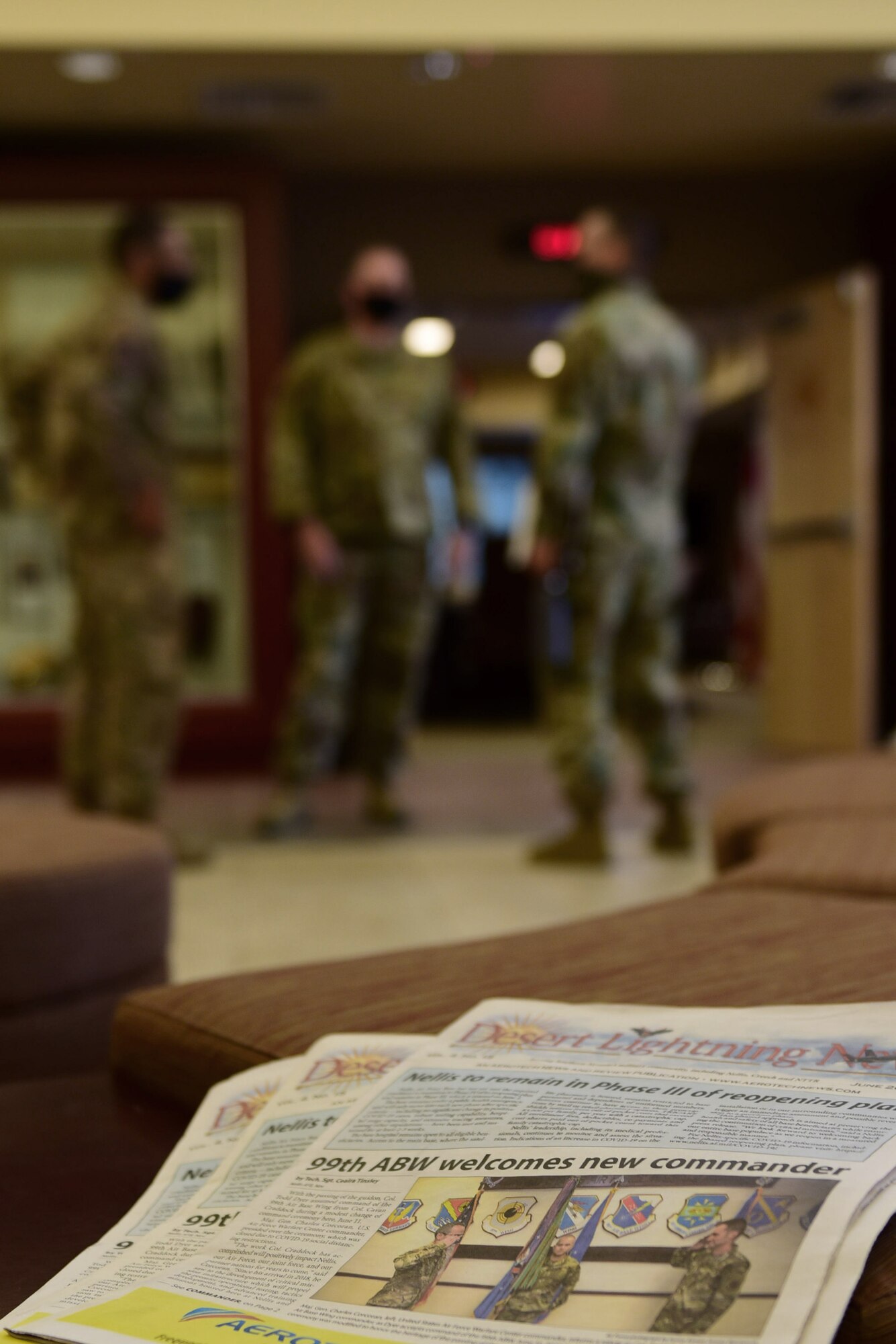 A newspaper with a picture of the most recent 99th Air Base Wing change of command ceremony is displayed in front of 432nd Wing and 99th ABW leadership on a stool.