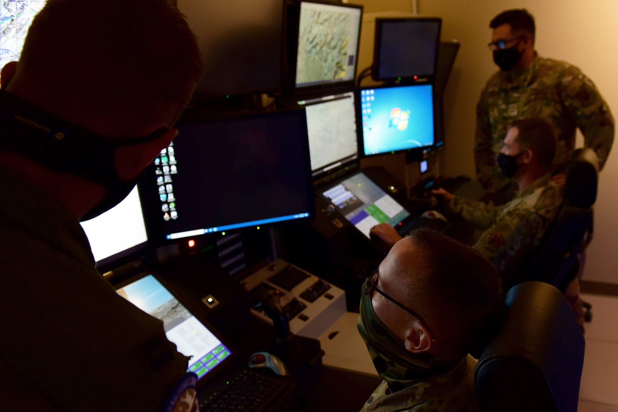 99th Air Base Wing leadership sit in an MQ-9 Reaper flight simulator with instructors.