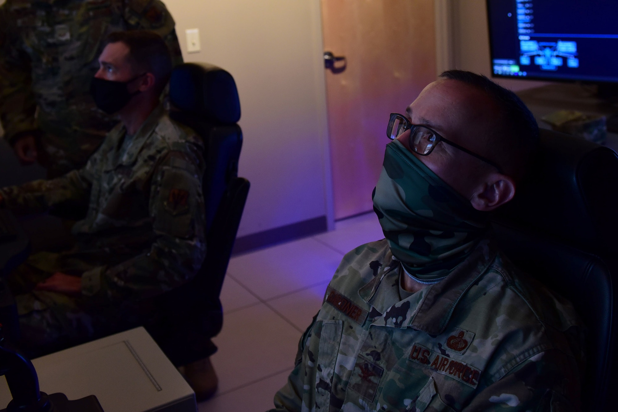 99th Air Base Wing vice commander looks up at a MQ-9 Reaper flight simulator screen.