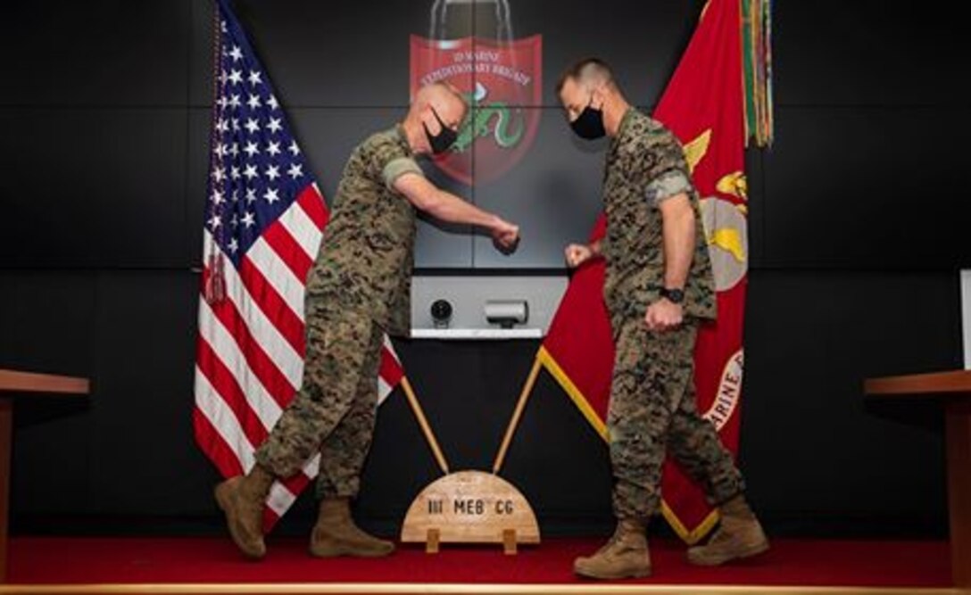 Maj. Gen. Paul J. Rock, left, outgoing commanding general of 3D Marine Expeditionary Brigade, and Brig. Gen. Kyle B. Ellison, right, incoming commanding general of 3D Marine Expeditionary Brigade, participate in a change of command ceremony at Camp Courtney, July 10, 2020. The ceremony represents the transfer of authority, responsibility, and accountability from the out-going commanding general to the incoming commanding general.