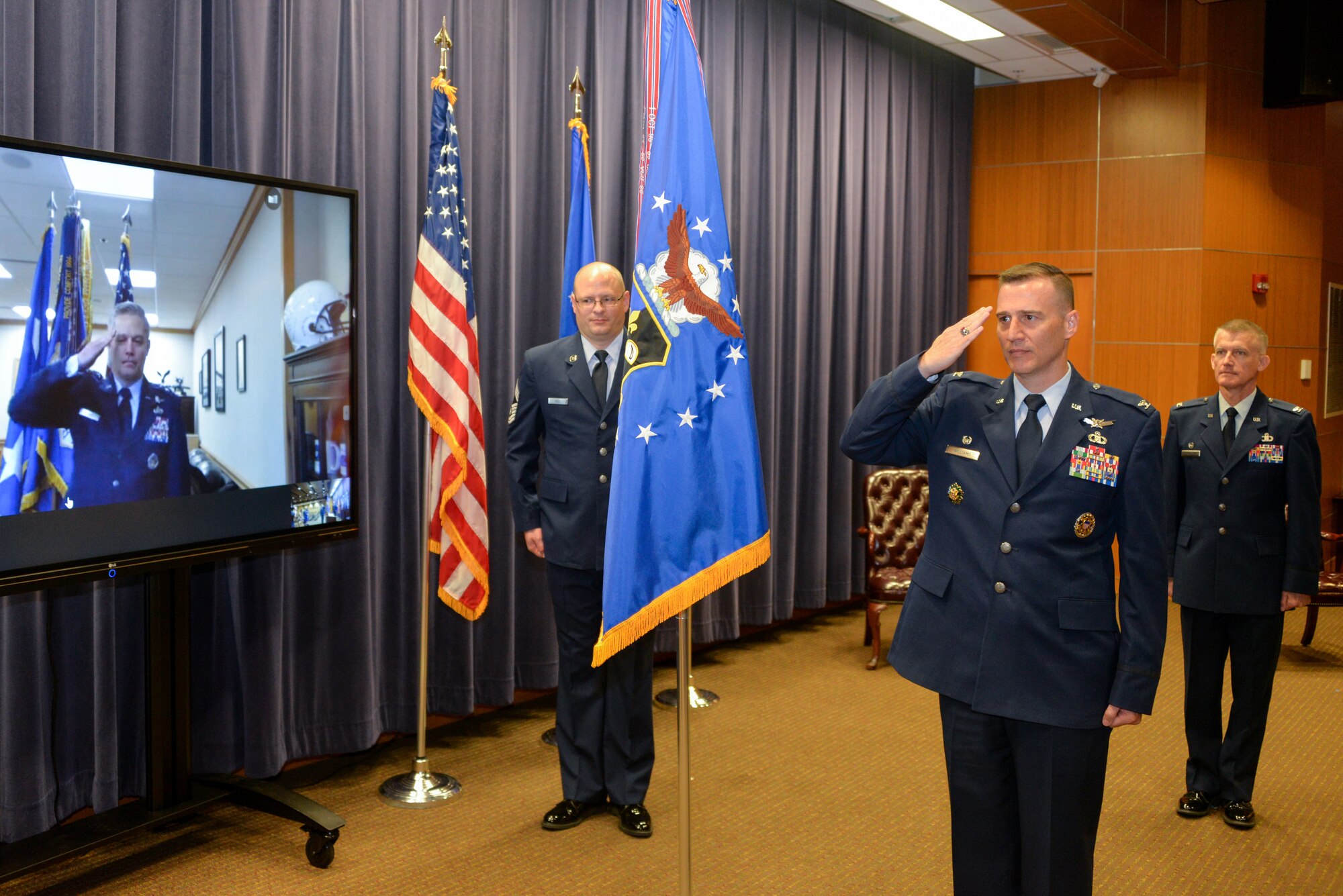 Lt. Gen. Timothy Haugh, Sixteenth Air Force (Air Forces Cyber) commander, salutes Col. Patrick Williams through a video conference link as he assumes command of the 557th Weather Wing during a change of command ceremony at the 557th Weather Wing headquarters building, Offutt Air Force Base, Nebraska, June 25, 2020.