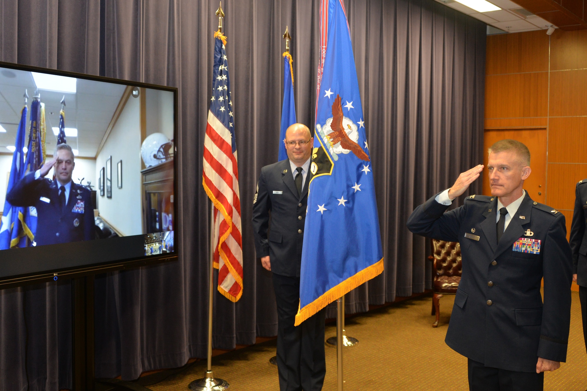 Lt. Gen. Timothy Haugh, Sixteenth Air Force (Air Forces Cyber) commander, salutes Col. Brian Pukall, 557th Weather Wing commander, through a video conference link as he relinquishes command of the wing during a change of command ceremony at the 557th Weather Wing headquarters building, Offutt Air Force Base, Nebraska, June 25, 2020.